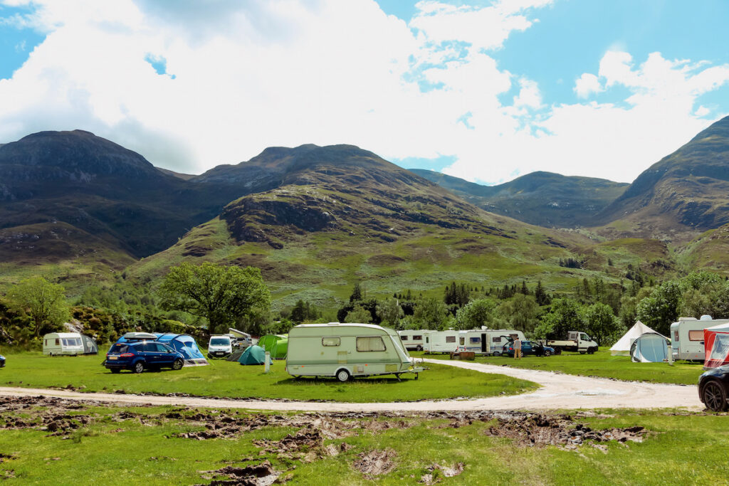 Campsite with tents and caravans with a mountain back-drop.