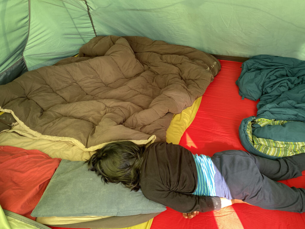 Sleeping bags in tent with a child sleeping across it
